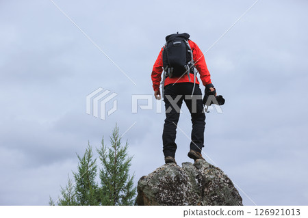 Successful hiker with camera on mountain top Successful hiker with camera on mountain top 126921013