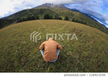 Woman hiker bow on the high altitude mountain top grassland Woman hiker bow on the high altitude mountain top grassland 126921030