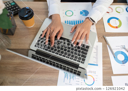 Remote Work Collaboration. Professional analyzing financial data on laptop and charts. 126921042