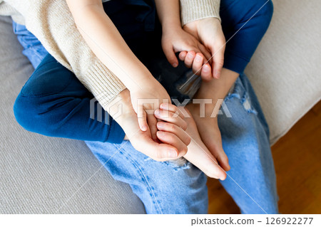 Close up of caucasian child and adult hands embracing in comforting gesture on couch Close up of caucasian child and adult hands embracing in comforting gesture on couch 126922277