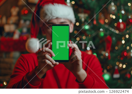 Portrait of a christmas man in santa hat holding smartphone with green screen 126922474