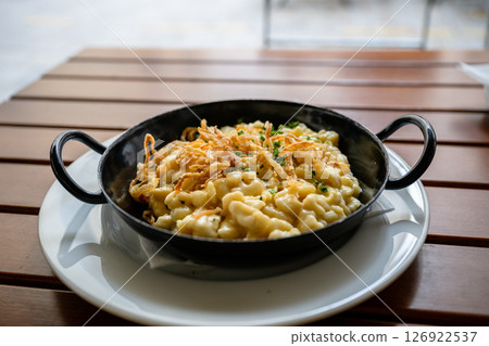 Traditional cheese spaetzle with crispy onions served in black pan on wooden table 126922537