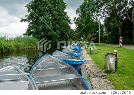 Row of aluminum boats mooring along canal in famous Giethoorn village in Netherlands 126922646