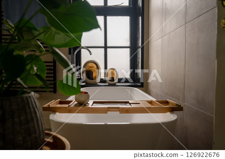 Interior of bathroom with bathtub, dressing table, shelving and large window Interior of bathroom with bathtub, dressing table, shelving and large window 126922676