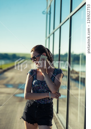 A young woman is talking intently near the transparent panels of the building. 126922733
