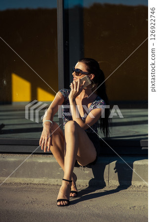 The young lady near the glass surface is engaged in an active phone conversation 126922746