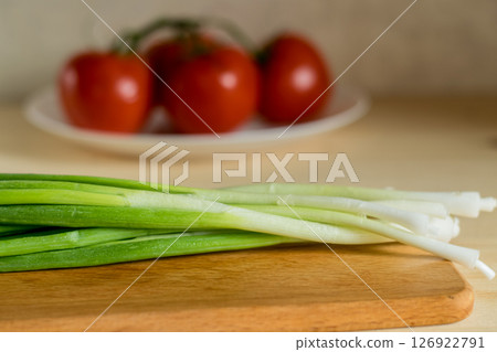 Close-up of young onions on a wooden kitchen board Close-up of young onions on a wooden kitchen board 126922791