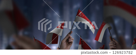 Singapore flags in their hands on a blurred urban background 126923782