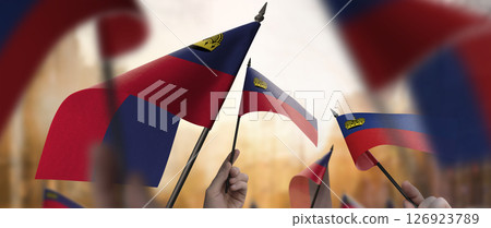 Liechtenstein flags in their hands on a blurred urban background 126923789