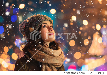 Beautiful woman embracing snowfall and sparkling holiday lights in festive season 126923931