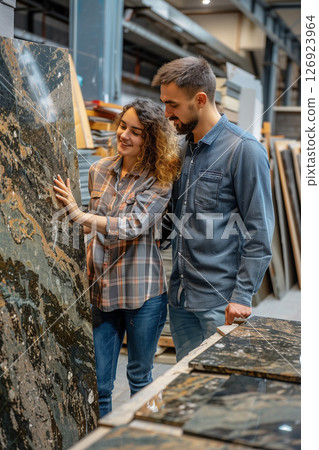 Young couple enthusiastically selecting large granite tiles for home renovation 126923964