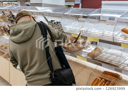 Man choosing bread on the counter. Buying fresh bread. Bakery. Man choosing bread on the counter. Buying fresh bread. Bakery. 126923999