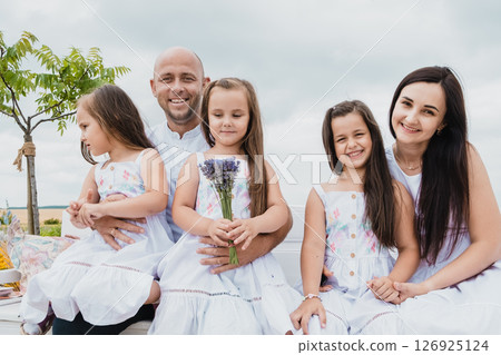 The family sits on an old wooden bench in a picturesque field The family sits on an old wooden bench in a picturesque field 126925124