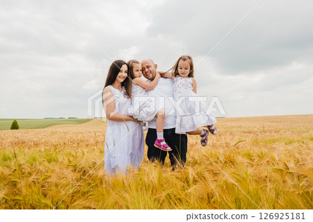 The family poses in front of a golden barley field 126925181