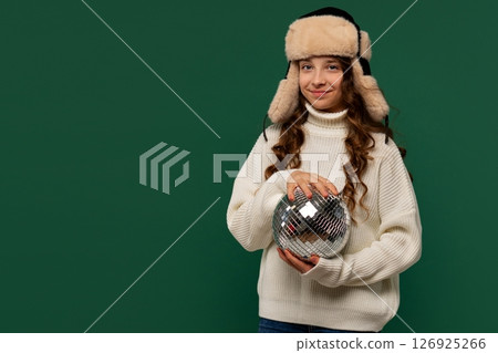 Young girl in fur hat posing with disco ball. Young girl in fur hat posing with disco ball. 126925266
