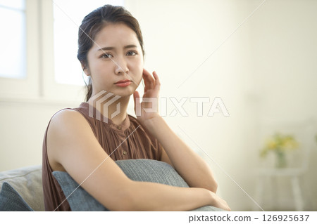 A woman in her 20s who is feeling unwell sitting on a sofa A woman in her 20s who is feeling unwell sitting on a sofa 126925637