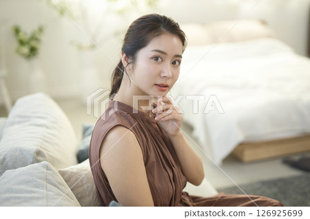 一位 20 多歲的女人坐在沙發上，美麗的形象 126925699