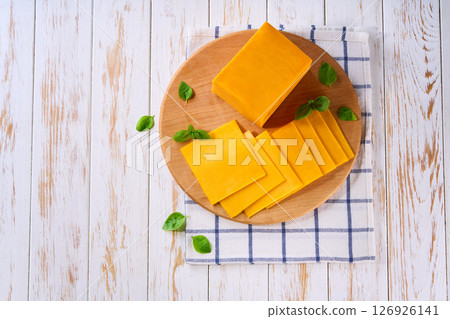 sliced natural cheese cheddar on on a white wooden table, top view. 126926141