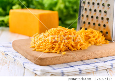 shredded cheddar cheese on a light kitchen table, selective focus. 126926142