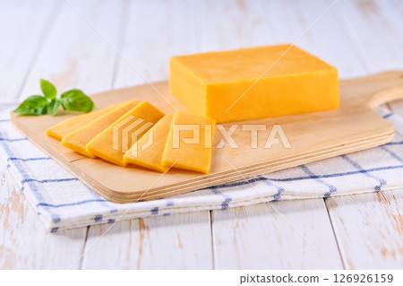 sliced natural cheese cheddar on on a white wooden table, selective focus. 126926159