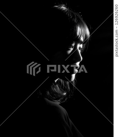 Profile portrait of a woman floating against a black background Profile portrait of a woman floating against a black background 126926260