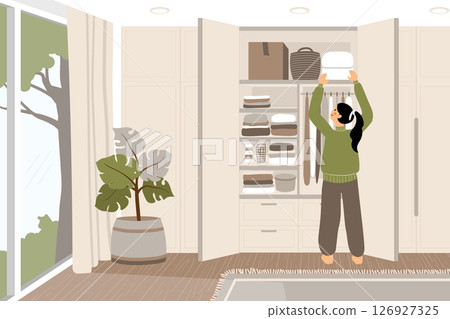 Back view of a woman storing blankets in a wardrobe. 126927325