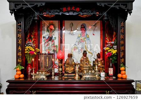 A scene from the festival site with statues of Buddha and incense lamps and offerings in the house. 126927659
