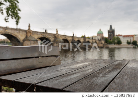 Empty wooden table and bench overlooking charles bridge in prague 126927688