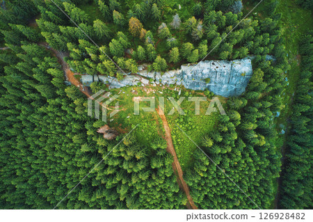 Aerial view of a big stone slab on a mountain slope forest in the middle of a sunny summer day. Aerial view of a big stone slab on a mountain slope forest in the middle of a sunny summer day. 126928482