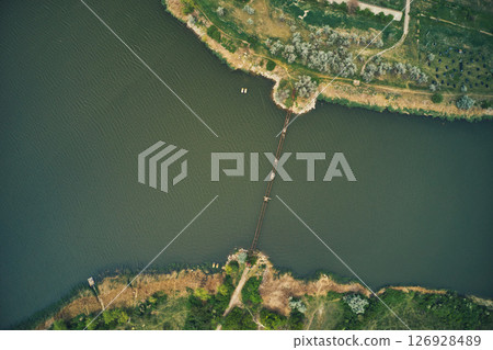 Aerial drone view of an old and broken bridge connecting one river bank to another 126928489