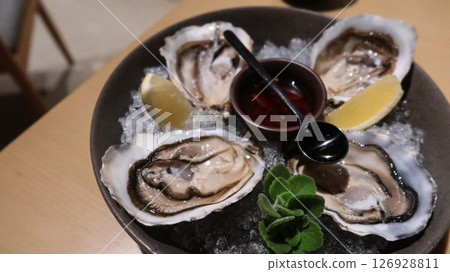 close up of four pieces of fresh raw oysters with vinegar and lemon slice on ice in a big plate with copy space close up of four pieces of fresh raw oysters with vinegar and lemon slice on ice in a big plate with copy space 126928811