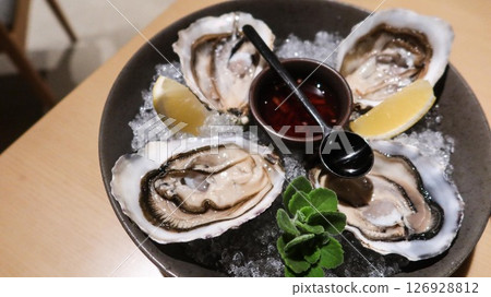 close up of four pieces of fresh raw oysters with vinegar and lemon slice on ice in a big plate with copy space close up of four pieces of fresh raw oysters with vinegar and lemon slice on ice in a big plate with copy space 126928812