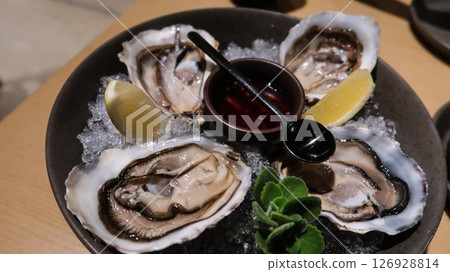 close up of four pieces of fresh raw oysters with vinegar and lemon slice on ice in a big plate with copy space close up of four pieces of fresh raw oysters with vinegar and lemon slice on ice in a big plate with copy space 126928814