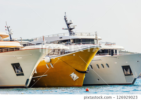 Line of many luxury smal cruise yacht boat ship docked Croatian bay harbor shore blue  clear water bright summer sunny sunset sunrise morning. Rich quality lifestyle. Boat vessel charter service 126929023