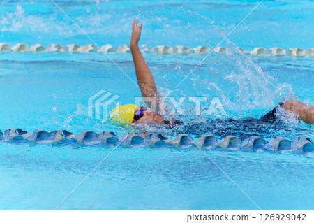 Swimmer child swims backstroke swimming style in a race swimming pool. Water sports and competition, learning to swim classes for children. 126929042