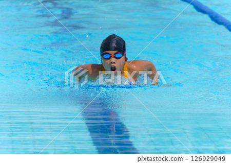 Swimmer child swims butterfly swimming style in a race swimming pool. Water sports and competition, learning to swim classes for children. 126929049