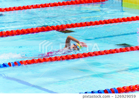 Swimmer child swims freestyle swimming style in a race swimming pool. Water sports and competition, learning to swim classes for children. 126929059