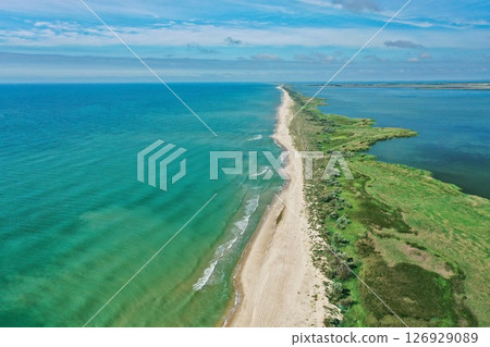 Aerial view of waves on a gritty tropical beach. Oncoming waves crashing against the sandy tropical shore over and over again. Aerial drone top view of sandy and wavy beach. Aerial view of waves on a gritty tropical beach. Oncoming waves crashing against the sandy tropical shore over and over again. Aerial drone top view of sandy and wavy beach. 126929089