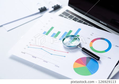 A document clipped with a graph, a magnifying glass, and a computer 126929113