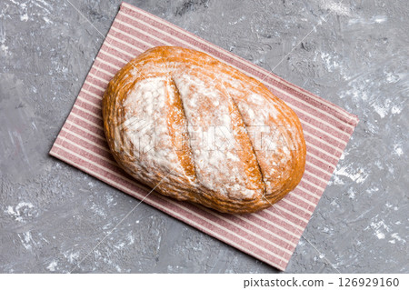 Freshly baked delicious french bread with napkin on rustic table top view. Healthy white bread loaf Freshly baked delicious french bread with napkin on rustic table top view. Healthy white bread loaf 126929160