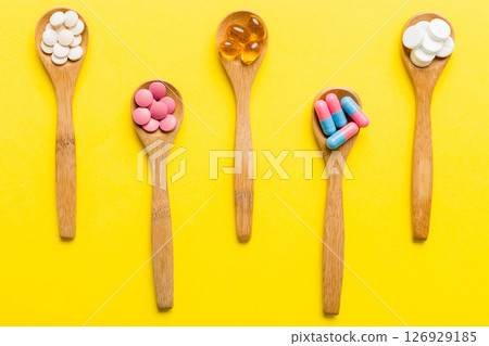 Vitamin capsules in a spoon on a colored background. Pills served as a healthy meal. Red soft gel vitamin supplement capsules on spoon Vitamin capsules in a spoon on a colored background. Pills served as a healthy meal. Red soft gel vitamin supplement capsules on spoon 126929185