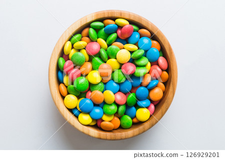 Multicolored candies in a bowl on a colored background. birthday and holiday concept. Top view with copy space 126929201