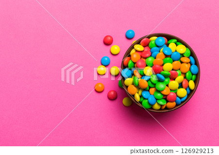 Multicolored candies in a bowl on a colored background. birthday and holiday concept. Top view with copy space Multicolored candies in a bowl on a colored background. birthday and holiday concept. Top view with copy space 126929213