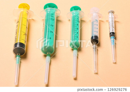 Top view of medical syringes with needles at orange background with copy space. Injection treatment concept 126929276