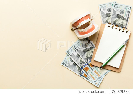 Flat lay composition with educational dental typodont model and money with notebook on colored table, top view. Expensive treatment 126929284