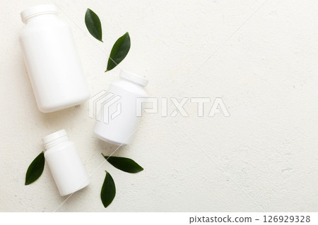 supplement pills with medicine bottle health care and medical top view. Vitamin tablets. Top view mockup bottle for pills and vitamins with green leaves, natural organic bio supplement, copy space 126929328