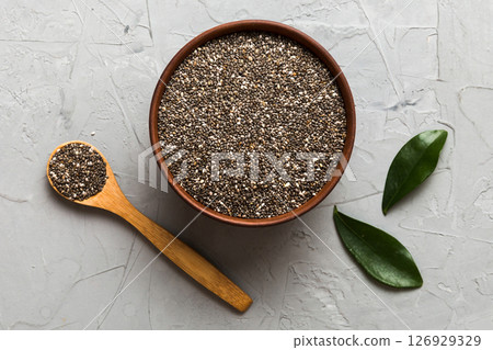 Chia seeds in bowl and spoon on colored background. Healthy Salvia hispanica in small bowl. Healthy superfood Chia seeds in bowl and spoon on colored background. Healthy Salvia hispanica in small bowl. Healthy superfood 126929329