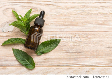 Natural Mint Essential Oil in a Glass Bottle. organic cosmetics with herbal extracts of mint on colored background 126929335