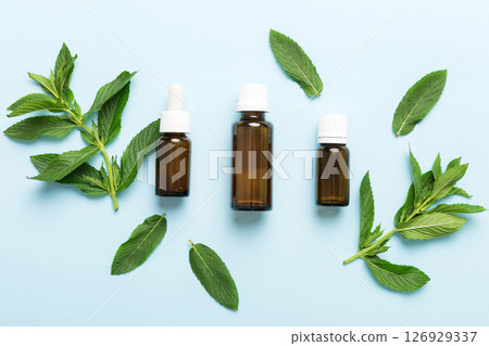 Natural Mint Essential Oil in a Glass Bottle. organic cosmetics with herbal extracts of mint on colored background Natural Mint Essential Oil in a Glass Bottle. organic cosmetics with herbal extracts of mint on colored background 126929337