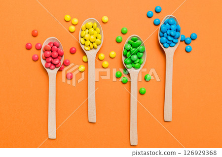 delicious colorful sweet candies on spoon on colored background . Confectionery decor top view with copy space 126929368